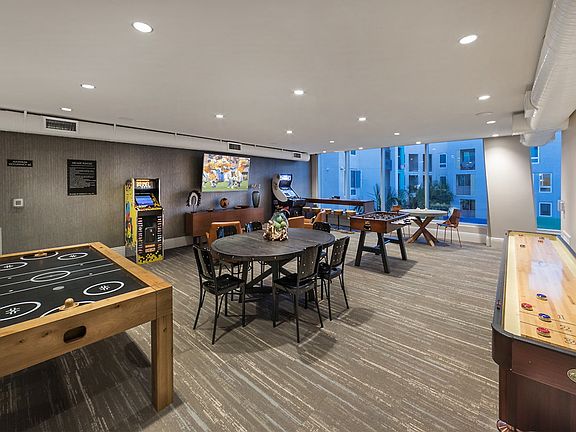 Recreations room with floor-to-ceiling windows, arcade games, shuffle board and air hockey.