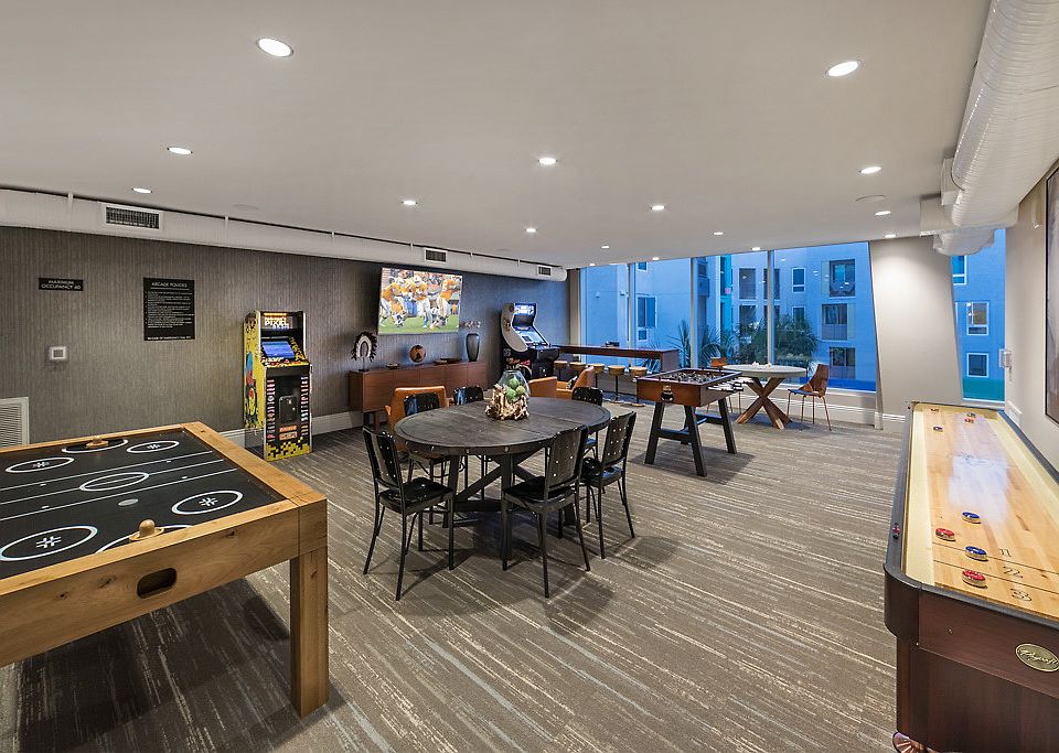 Recreations room with floor-to-ceiling windows, arcade games, shuffle board and air hockey.