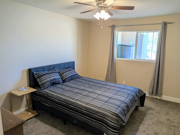 Bedroom 1 with Queen bed, dresser, hangers, room darkening curtains, laundry basket, nightstand, sound machine, ceiling fan,