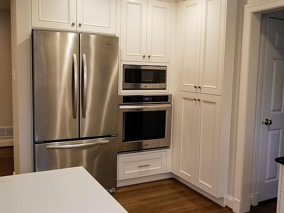 A view of the kitchen pantry, refrigerator, microwave and oven.