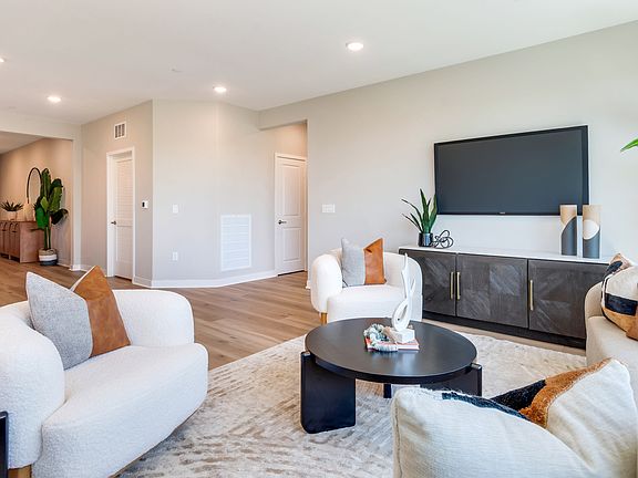 A modern and cozy living room with white furniture, a large TV, and various decorative elements, set