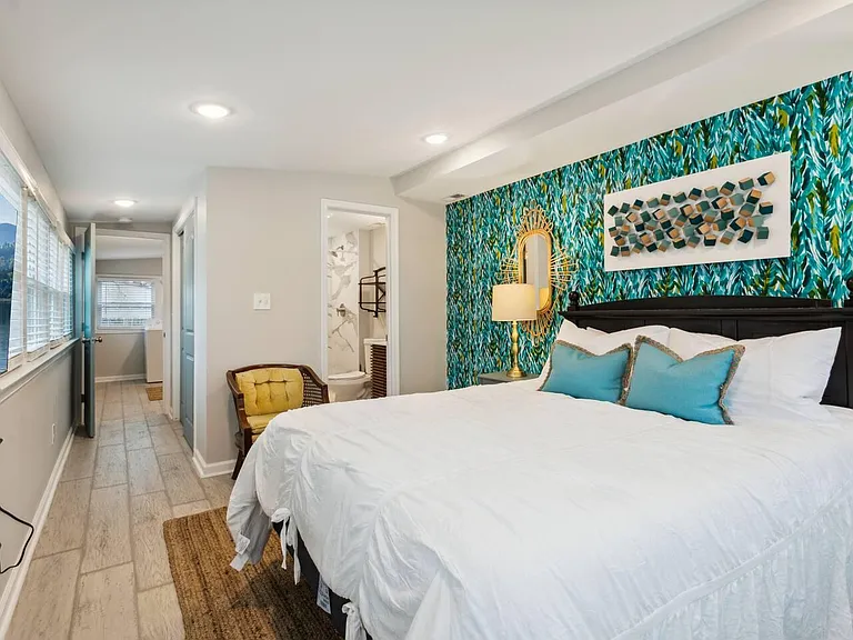 Spacious bedroom with a large window, tile flooring, and easy access to an adjacent full bath for added convenience.