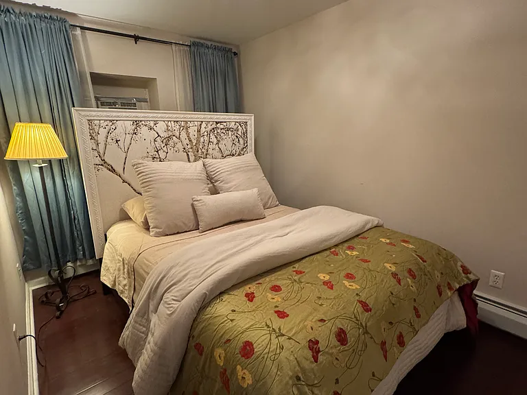 Bedroom with a/c, overhead lighting and floor lamp.