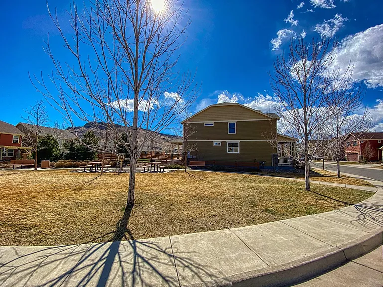 Street view with adjoining common area/park with picnic tables, neighborhood book exchange, and plenty of room for outdoor activities.