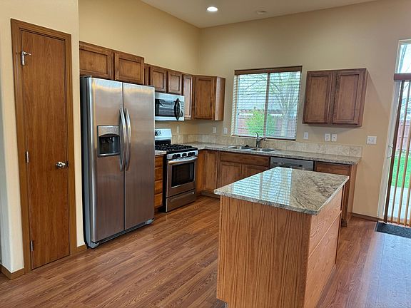 Kitchen with island, pantry, gas range, microwave and dishwasher.