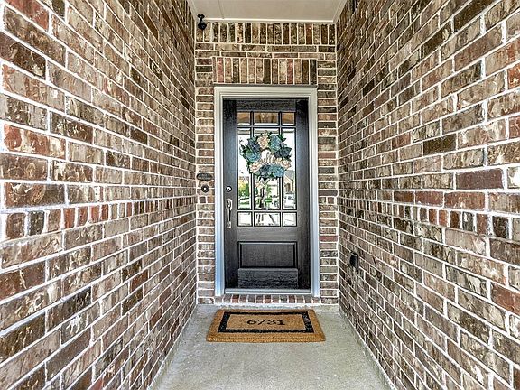 Approaching the front door you will see the beautiful brick elevation, covered front porch, and dark stained front door with glass detailing!