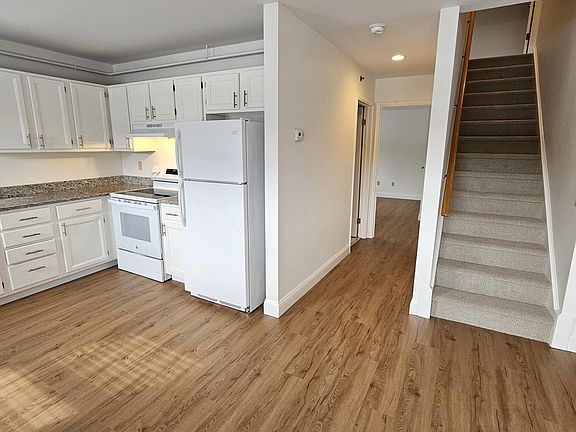 View from Living Area to kitchen, stairs to 2nd floor and hallway (bath on left) to Primary Bedroom