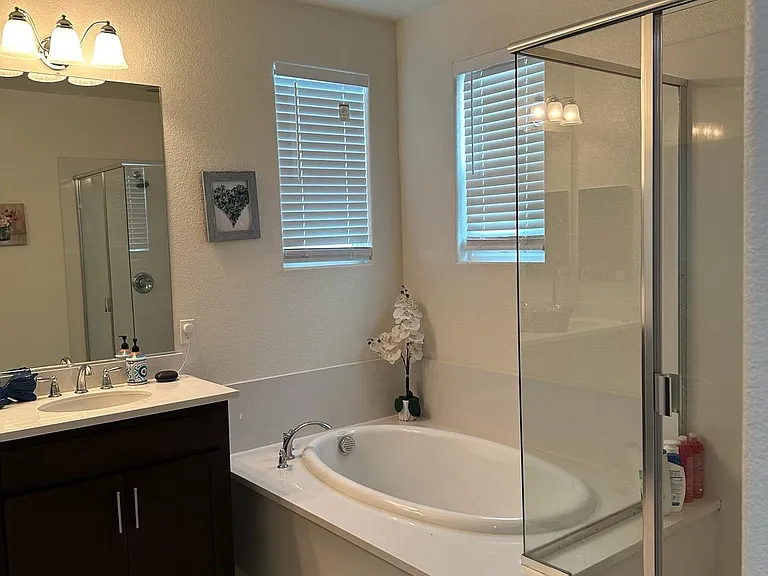 Indulge in luxury with our master bath oasis featuring double sinks, a sleek glass-wall shower, a inviting bathtub, an attached toilet, and a spacious closet. Welcome to your private retreat. ___