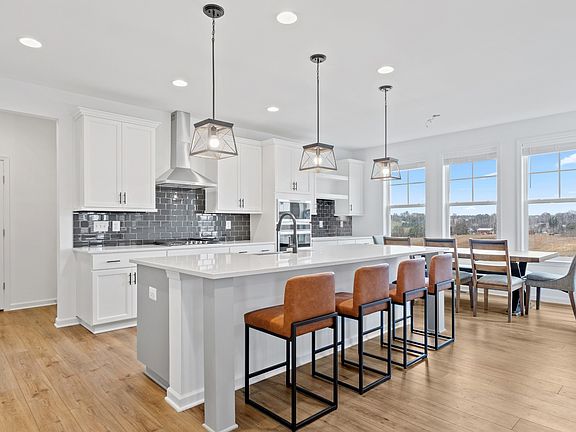Island kitchen with white cabinets in a DRB Homes Bridgeport model at the Prinland Heights community