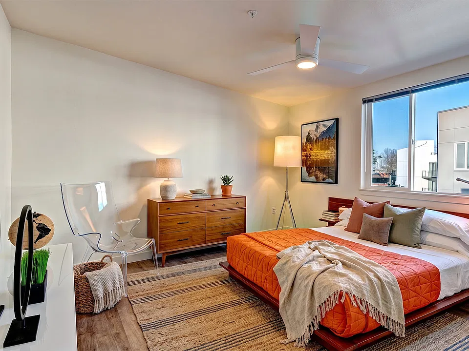 Room for a queen bed, a dresser and a reading chair, with a ceiling fan and a wide window.