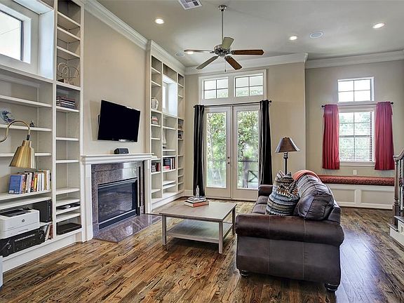 This second floor living room with elegant hardwood floors, gas-log fireplace, built-in bookcases, French doors leading to a balcony, soaring ceilings with decorative crown moulding and built-in window seat is truly impressive!