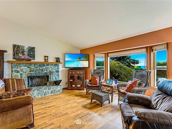 Living Room has rock fireplace,laminate flooring, wainscot walls, bay windows that lookout to Burrows 
