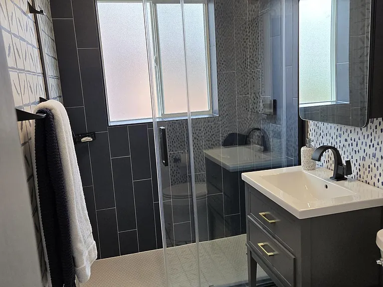 Rommy bathroom with new large insulated window:
Kohler toilet, sink, faucet
Wall to wall shower doors