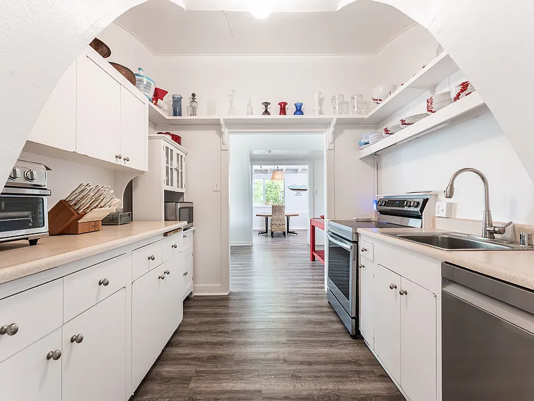 Galley-style kitchen featuring ample cabinet storage, updated appliances, and luxury vinyl flooring.