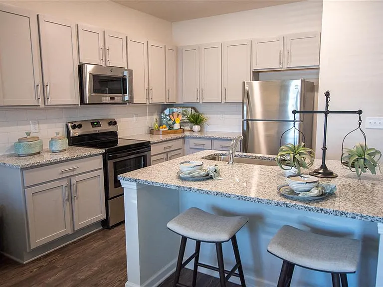 Kitchen island with bar seating. looking into the full kitchen with a view of the washer and dryer off to the left.