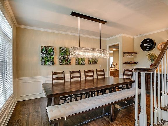 Brilliant chandelier illuminates the formal dining room featuring crown molding details, painted wainscot, espresso hardwood flo