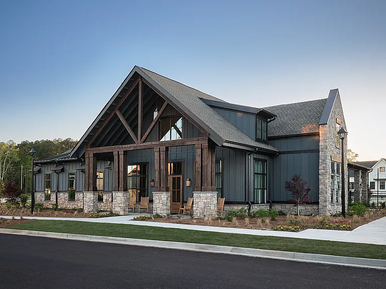 Clubhouse exterior with ample parking and rocking chairs on the front porch.