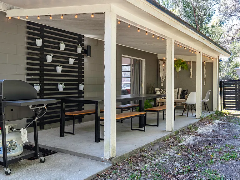 Covered porch off living room outdoor dining area, seats ten, with string lights and large dual fuel (charcoal and propane) grill - Day time