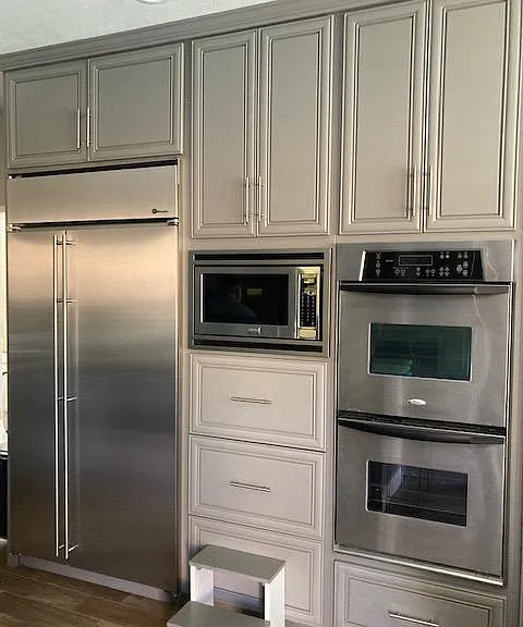 Kitchen with microwave, double ovens, and main refrigerator. Multiple other refrigerators in garage.