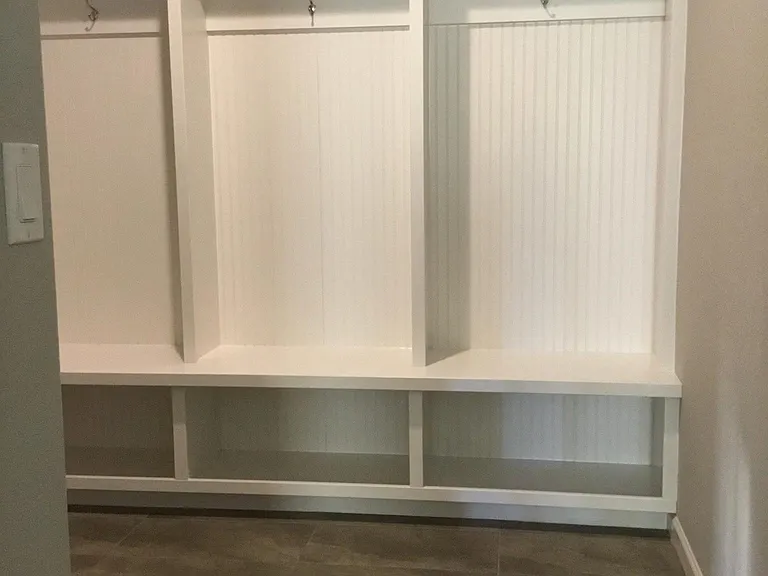 Cubbies for jackets, boots and bench over tile floor.