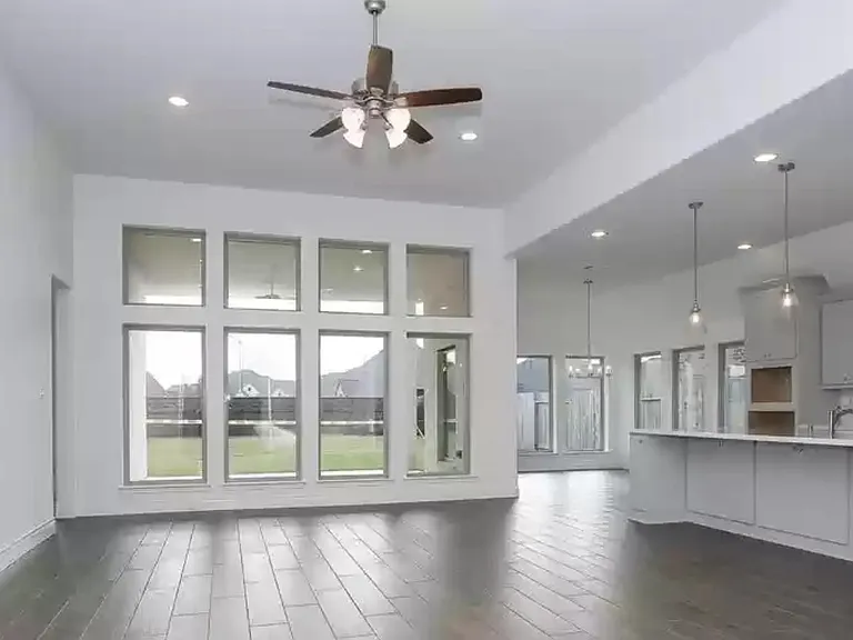 Family room 12 ft ceiling and wall of windows. Looking out to the covered patio. Kitchen on the right.