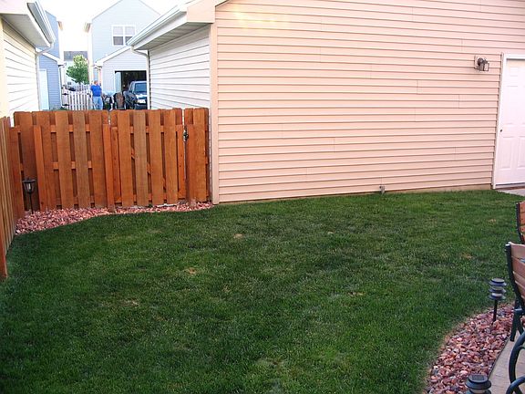 view from side yard gate toward garage. rock landscaping. 
