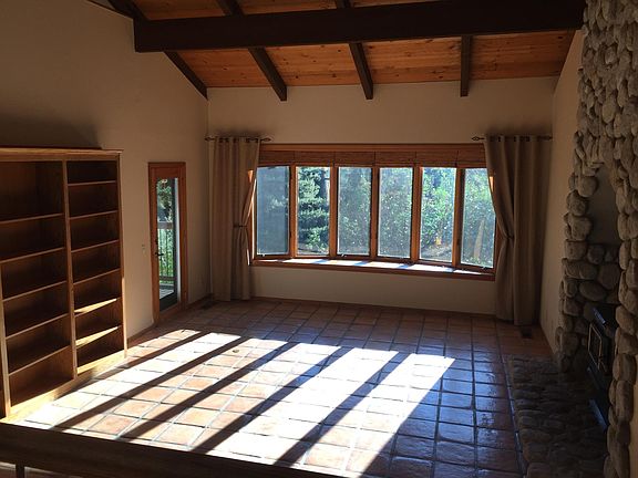Living room with large bow window, wood burning stove and built in bookcase