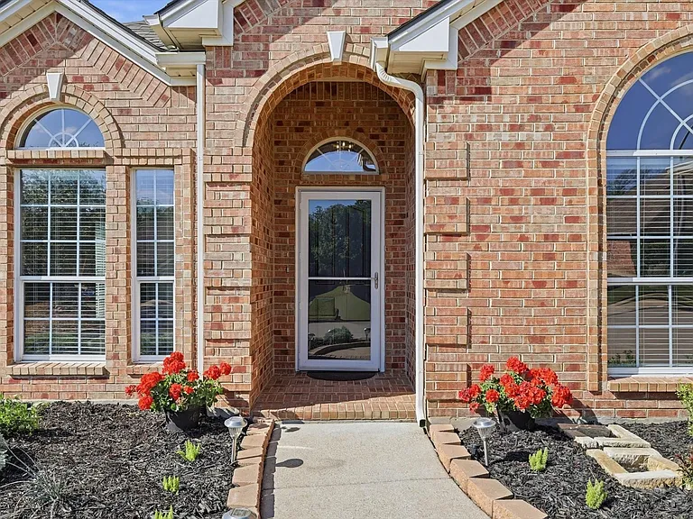 Brick exterior featuring an arched entryway, decorative stone window accents, and multiple arched windows with grilles