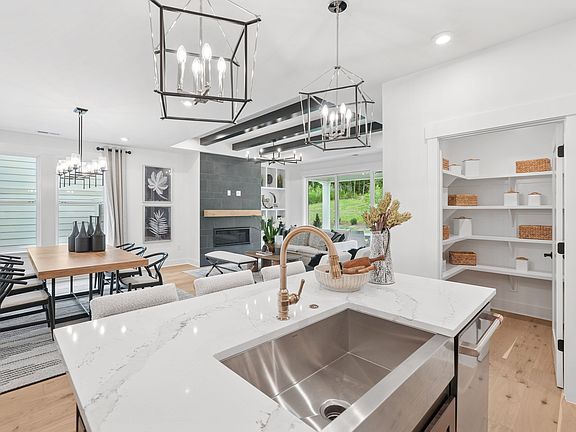 A modern, open-concept kitchen with a large stainless steel sink, wooden countertops, and a dining a