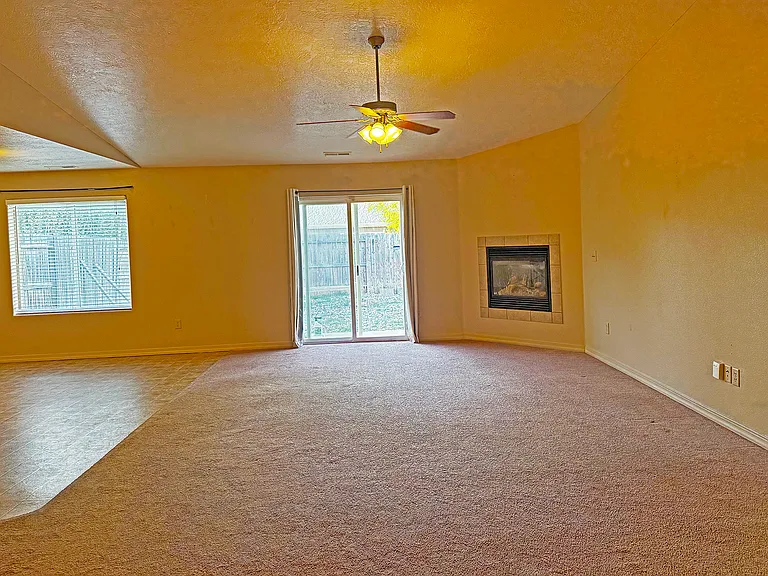Great room with patio door, fireplace on the right and dining area on the left