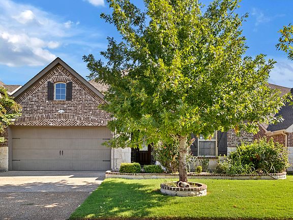Traditional home featuring brick and stone siding, concrete driveway, a 2-car garage, and a front lawn