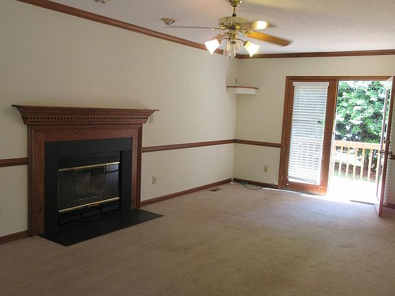 Another view of the living room - with ceiling fan, wood-burning fireplace, and access to the back deck!