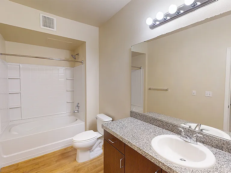 Apartment bathroom with large soaking tub and wood-style flooring.
