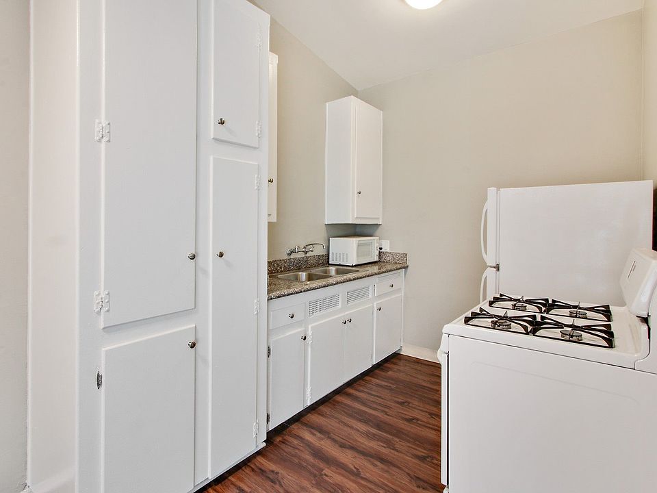 Kitchen With White Appliances, Refrigerator, Gas Range, Microwave, Stainless double kitchen sink with granite countertops, White kitchen cabinets, wood-style flooring