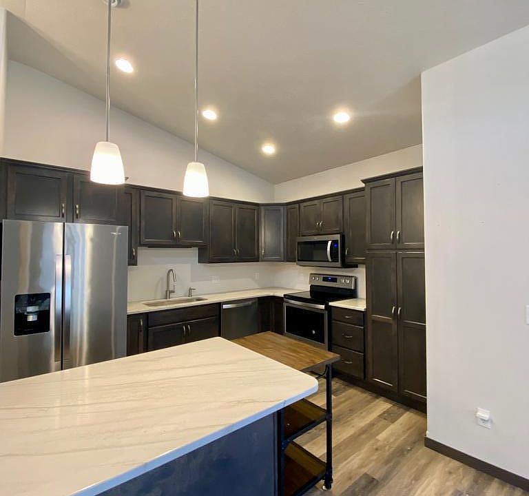 Kitchen with stainless steel appliances, quartzite countertops and island with bar seating