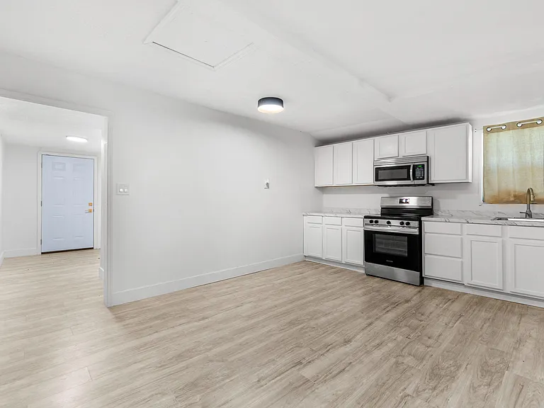 Open kitchen with ample white cabinetry, generous counter space, and stainless steel range with over-the-range microwave.
