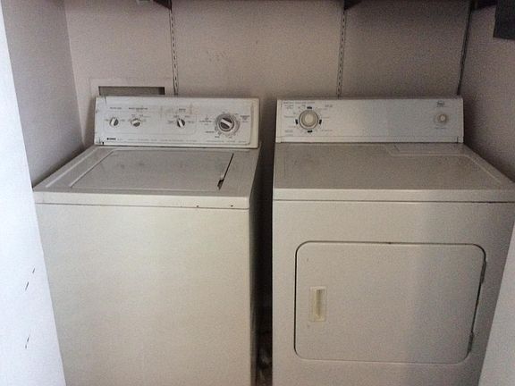 Washer/dryer area with plenty of shelving above.  Washer ava