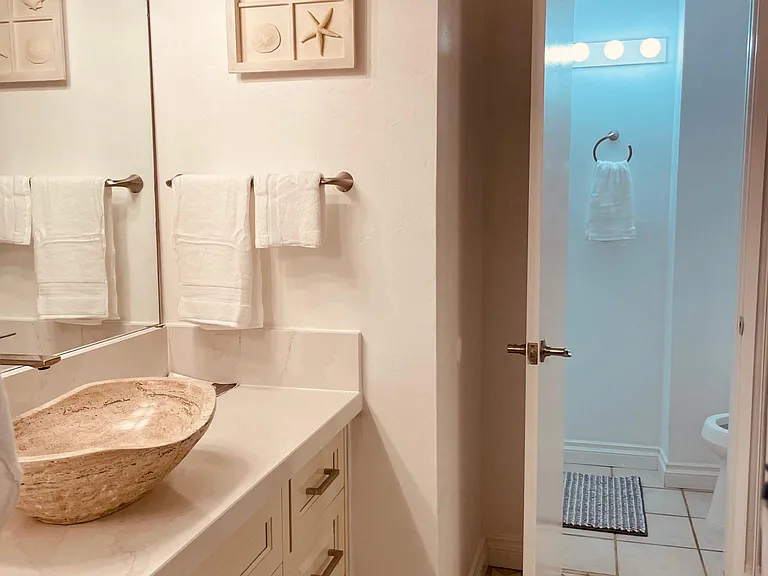 First bathroom with stylish natural stone sink & counter top. Large mirrored closet doors