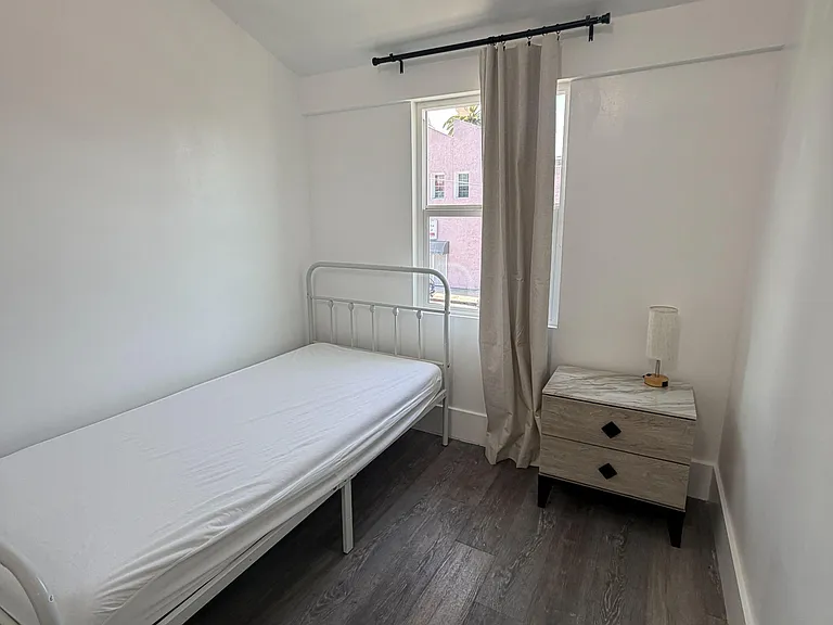 Private bedroom with a twin bed, nightstand, and a window with curtain panel for comfortable everyday living.