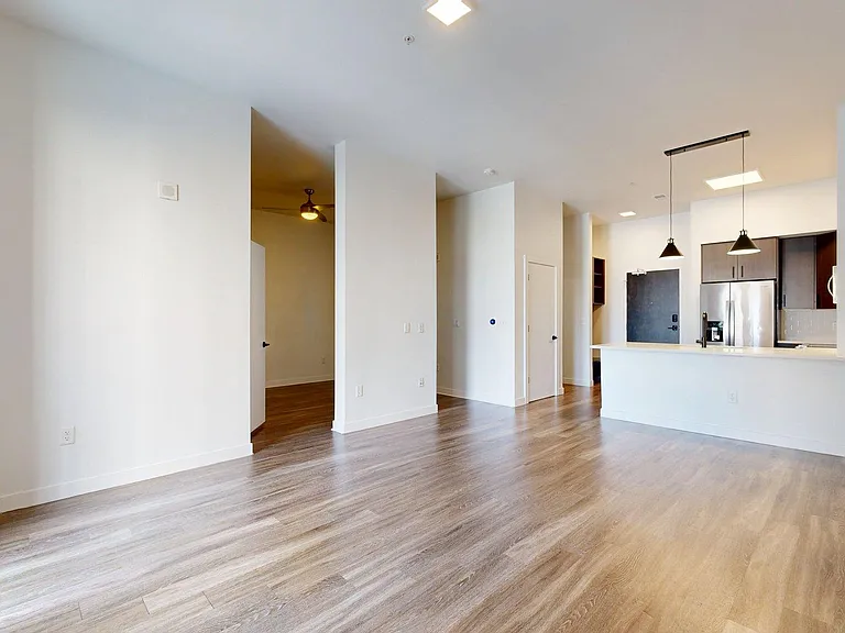 Apartment Living Room with light wood flooring and kitchen in view