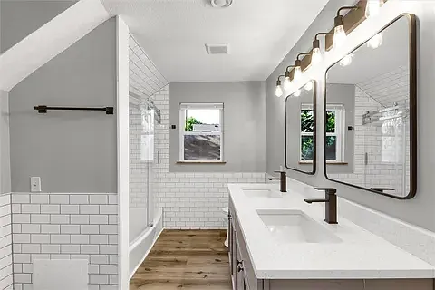 Tastefully updated bathroom with two sinks, a bath tub and a toilet. The bathroom is accessible from the master bedroom and the hallway.