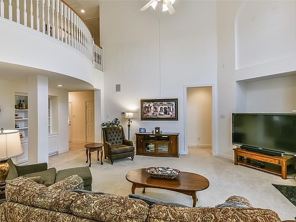 Family room surrounds a fireplace and features high ceilings plus built ins.