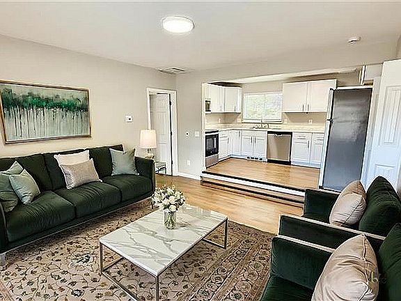 Charming living room with elegant decor, plush sofas, and a cozy open-concept kitchen featuring modern appliances and abundant natural light.