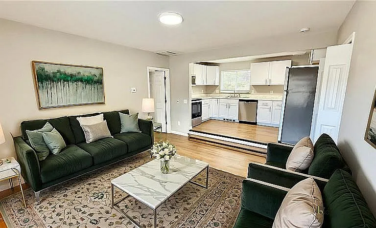 Charming living room with elegant decor, plush sofas, and a cozy open-concept kitchen featuring modern appliances and abundant natural light.