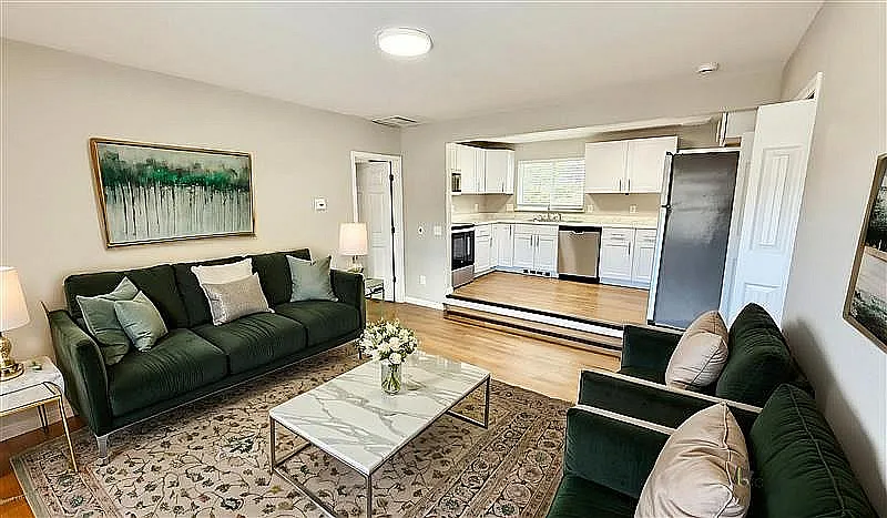 Charming living room with elegant decor, plush sofas, and a cozy open-concept kitchen featuring modern appliances and abundant natural light.