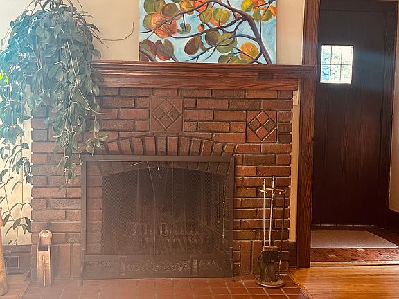 Entry into the LR with red brick fireplace. Wood floors throughout.