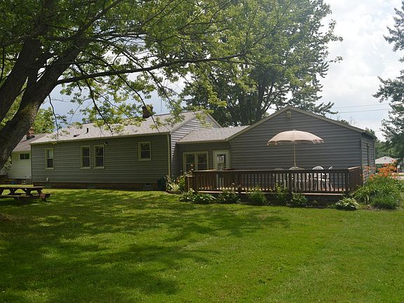 Rear view showing patio deck, sunroom entry, and picnic table.