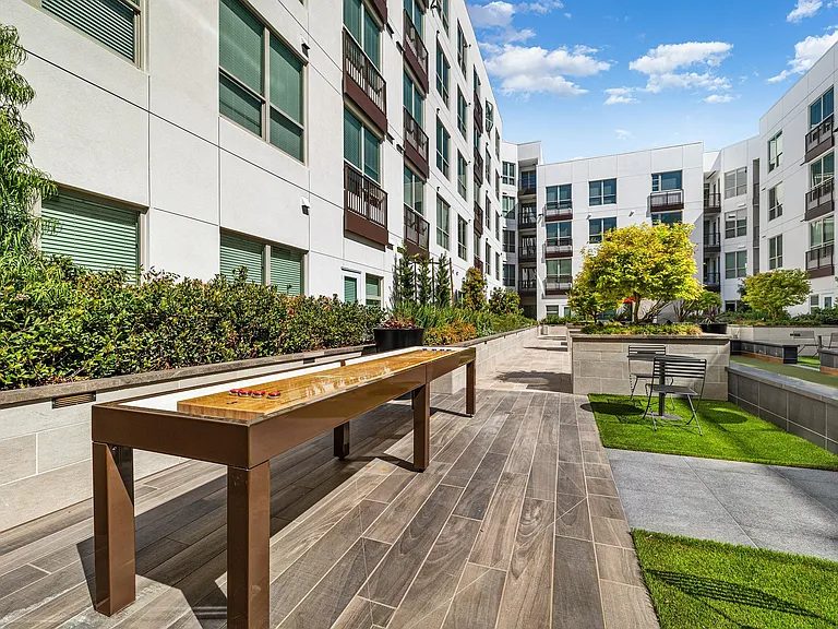 Outdoor shuffleboard table on landscaped terrace for residents