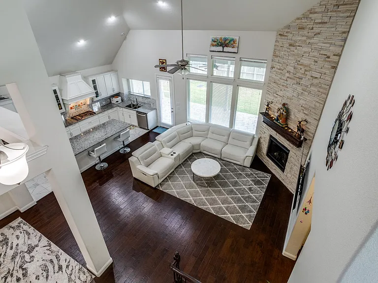 Living room featuring high vaulted ceiling, a stone fireplace, ceiling fan, sink, and dark hardwood / wood-style flooring