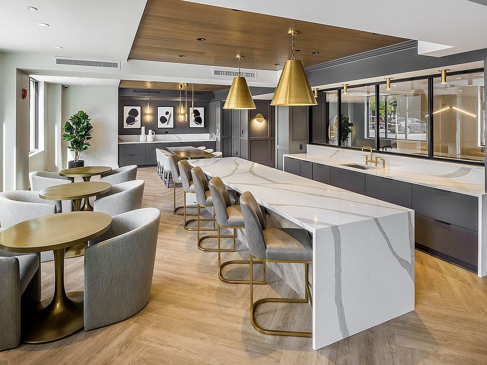 Luxurious modern light-filled kitchen with stylish stone island, elegant leather seating, large windows and contemporary lighting accents at Parkside Place, apartments in Cambridge, MA